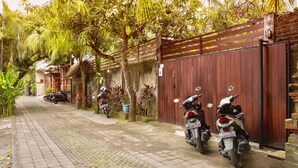 Uma trilha pavimentada ladeada por motocicletas estacionadas, uma cerca de madeira e vegetação exuberante.