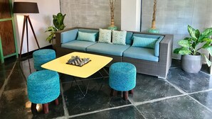 Uma sala de estar moderna com um sofá, dois pufes, uma mesa de centro e plantas decorativas.