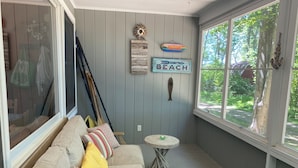 A cozy room with a beige couch, a small round table, and a window with a view of greenery.