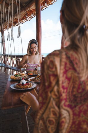 A wooden deck with a table set for a meal, overlooking a body of water.