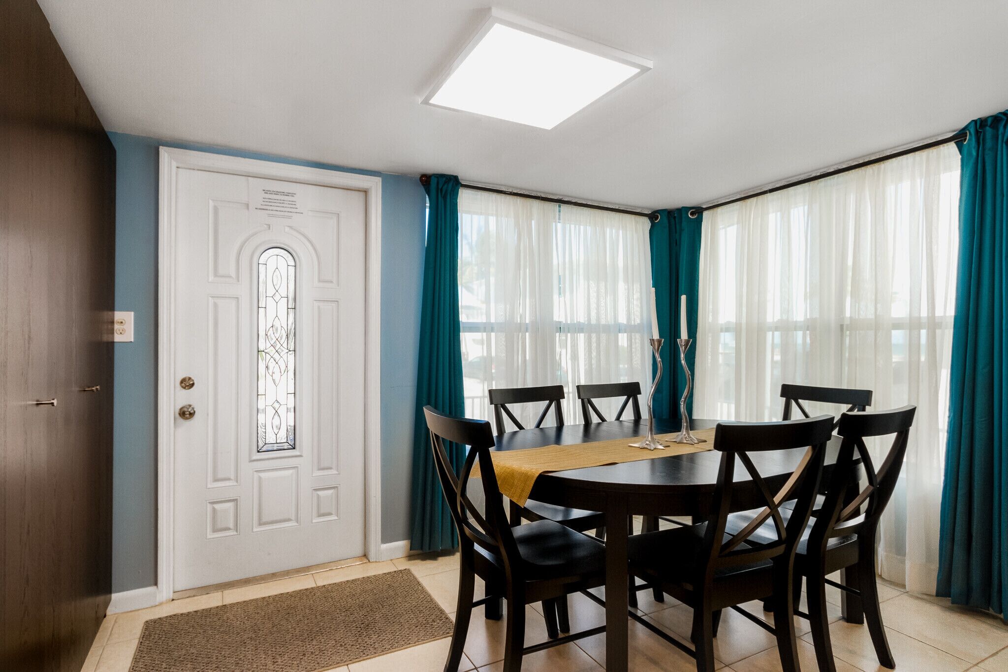 A dining area with a round table, six chairs, and a wooden floor mat.