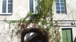 Un edifici amb un portal d'arc de pedra, una porta verda i una escala que condueix a un nivell superior.