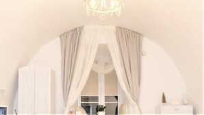 Una habitació amb un penjador de cristall, una porta apuntada i un moble blanc amb objectes decoratius.