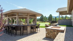 Une terrasse extérieure avec un bar, des sièges en pierre et une vue sur un terrain de golf.