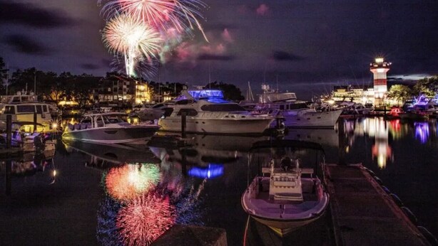 A marina at night with boats docked, a lighthouse, and fireworks in the sky. - July 4th Week MARRIOTT'S HARBOUR CLUB AT HARBOUR TOWN excellent location in town (Hilton Head Island)