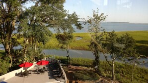 A deck with outdoor seating overlooking a body of water and a grassy area. - July 4th Week MARRIOTT'S HARBOUR CLUB AT HARBOUR TOWN excellent location in town (Hilton Head Island)