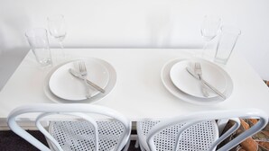 A white dining table with two sets of cutlery and glasses, surrounded by white chairs. - Regent Retreat - Sleeps 15, BBQ, pool (Moama)