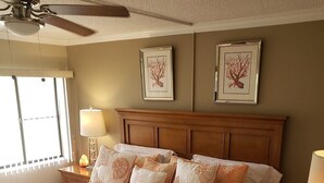 Una cama bien hecha con una colcha estampada de flores, un cabecero de madera y dos cuadros colgados en la pared.