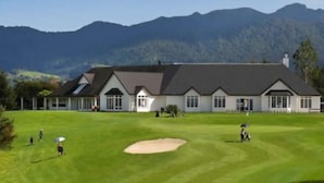 A golf course with a clubhouse and a large building with a sloped roof.