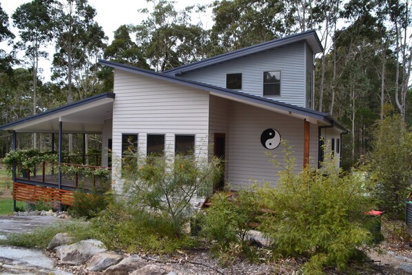 A modern two-story house with a covered porch and a circular window.