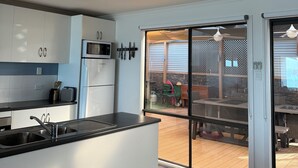 A modern kitchen with white cabinets, a black countertop, and a sliding glass door leading to an outdoor patio area.