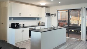 A modern kitchen with white cabinets, a central island, and a dining area with a table and chairs.