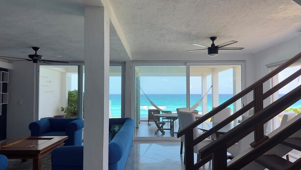 A spacious living area with a view of the ocean, a hammock, and a staircase leading to a balcony. - Casa Pelicano by B&G - Beach Front Villa Cancún Hotel Zone (Cancún)