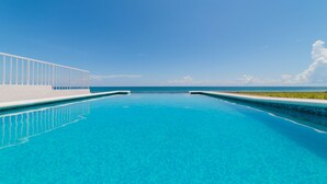 A clear blue pool with a white deck and a view of the ocean. - Casa Pelicano by B&G - Beach Front Villa Cancún Hotel Zone (Cancún)