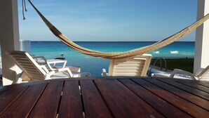 A hammock over a wooden table with white chairs, overlooking a pool and the ocean. - Casa Pelicano by B&G - Beach Front Villa Cancún Hotel Zone (Cancún)