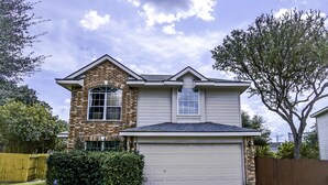 A two-story house with a garage, brick facade, and a small front yard. - A Bit of Country, All the Perks of the City (Helotes)