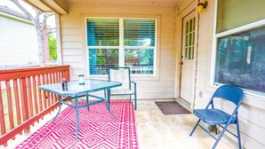 A covered porch with a table and chairs, a red patterned rug, and a view of the house through a window. - A Bit of Country, All the Perks of the City (Helotes)