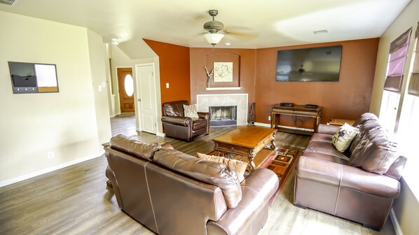 A living room with a fireplace, leather sofas, a coffee table, and a TV.