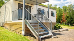 A single-story mobile home with a covered porch and a staircase leading to the entrance. - High View Accommodation #6 (Freemans Reach)