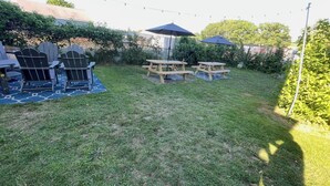A backyard with a wooden table and chairs, a covered picnic table, and a blue outdoor rug. - Convenient, Modern Thompson s Point 3-Bed Flat (Portland)
