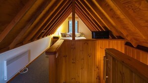 A cozy attic bedroom with wooden beams, a bed, a desk, and a window. - Echo Base – Alpine Family Retreat, Dinner Plain (Dinner Plain)