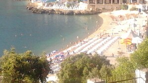 Eine Küstenlandschaft mit Strand, Pool und einem Gebäude mit rotem Dach.