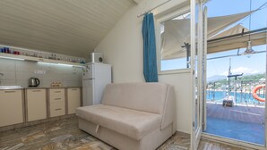 Eine kleine Küche mit einer Couch, einem Kühlschrank und einem Fenster mit Blick auf einen Poolbereich.