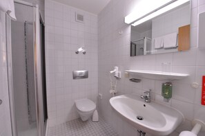 A bathroom with a shower, toilet, sink, and a mirror.