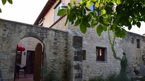 Un edificio de piedra con un arco de entrada, una ventana pequeña y una escalera que lleva a un espacio al aire libre.