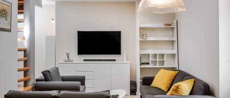 Un salon moderne doté d’un téléviseur à écran plat, de canapés gris et d’un meuble de rangement blanc.