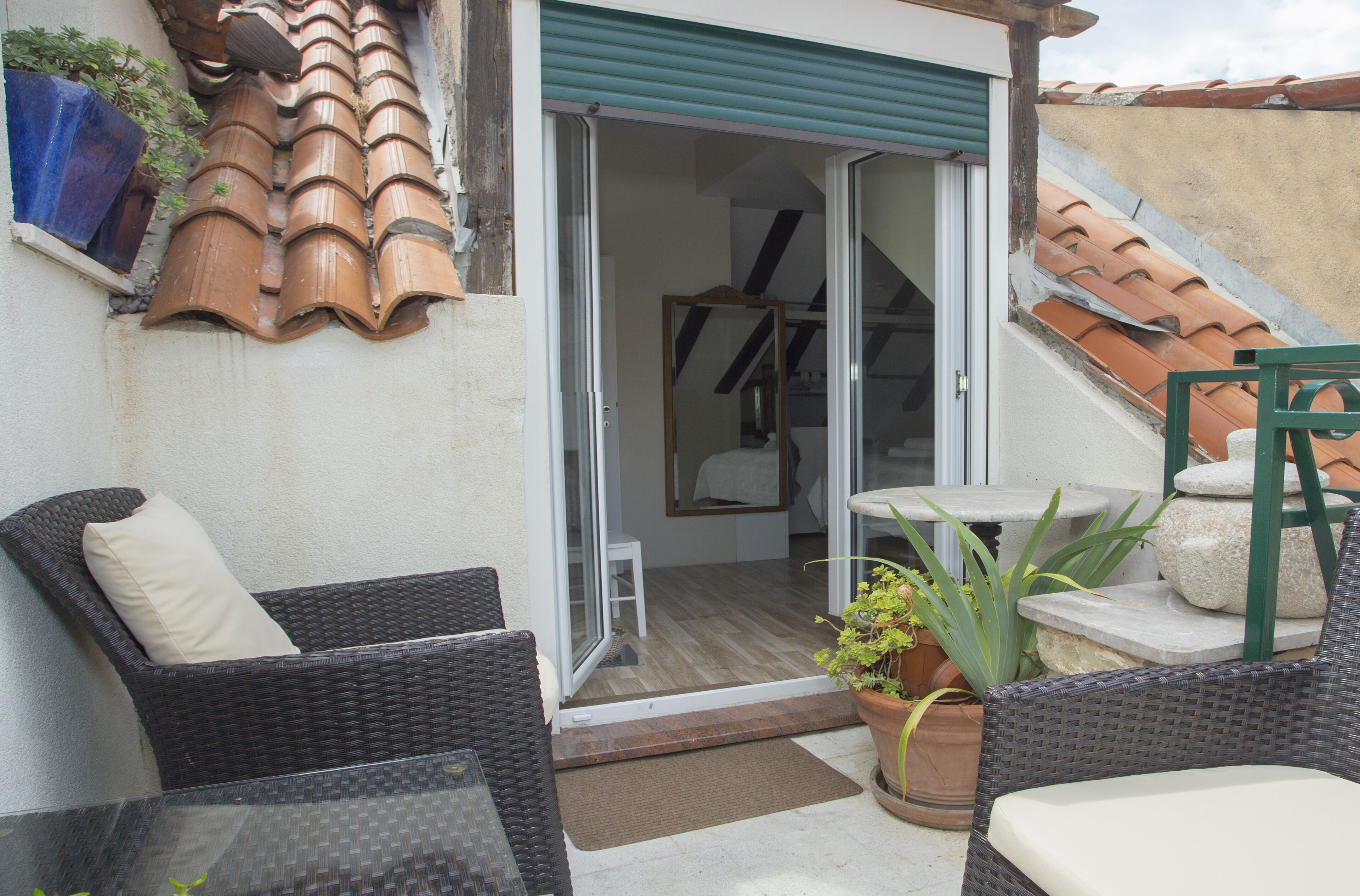 Un patio con mobiliario de mimbre, una mesa de vidrio y una planta en maceta.