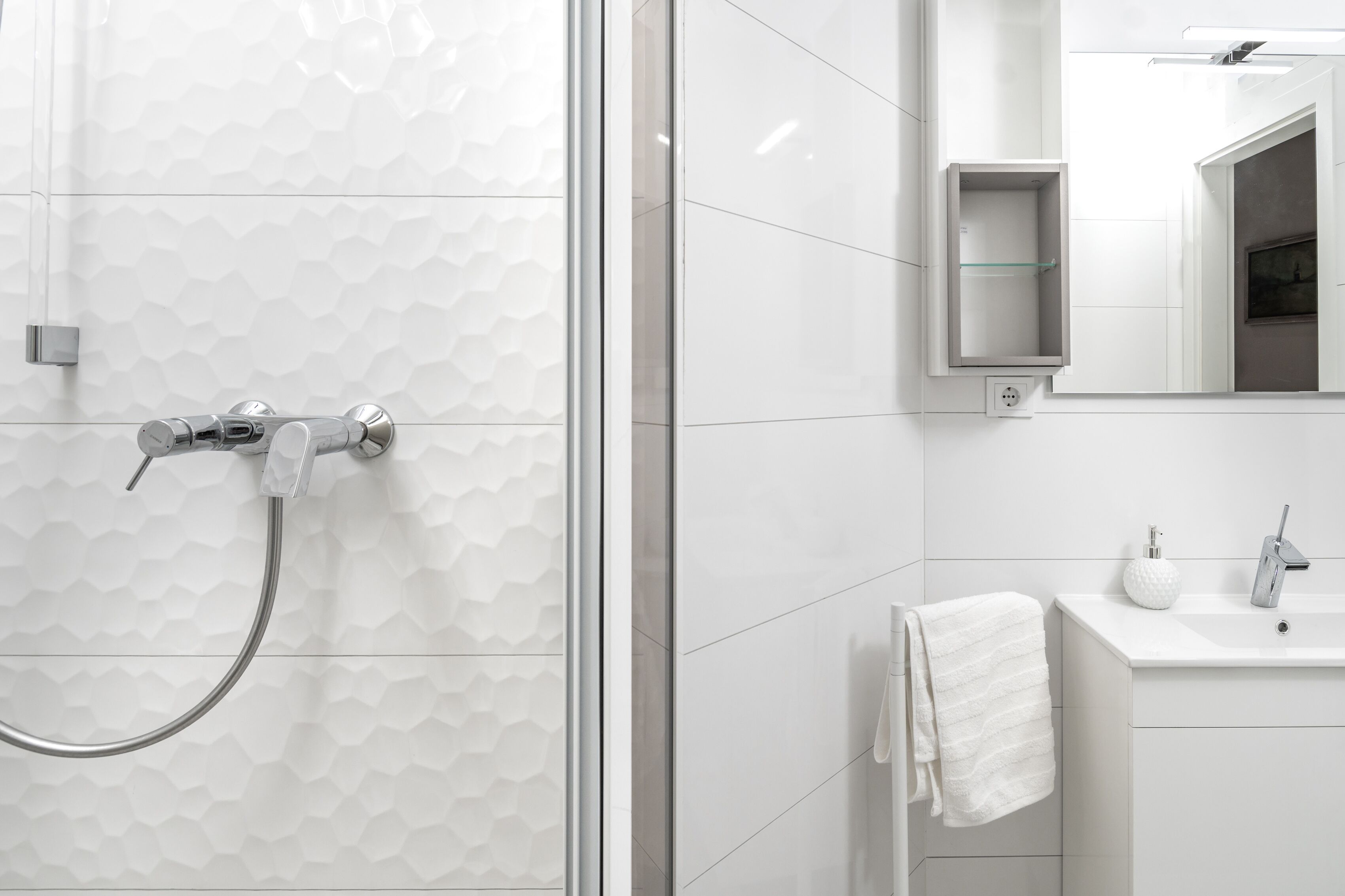 A modern bathroom with a shower, a sink, and a mirror.