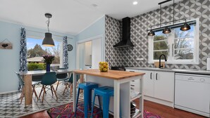 A modern kitchen with white cabinets, a wooden island, and blue bar stools. - Hamilton house - private, central & sunny! (Hamilton)
