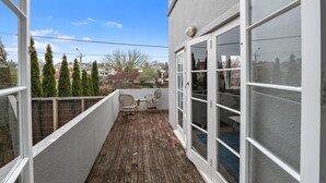A balcony with a wooden floor, two chairs, and a table. - Hamilton house - private, central & sunny! (Hamilton)