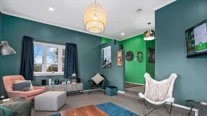 A modern living room with teal walls, a wooden coffee table, a grey sofa, a fluffy chair, and a blue rug. - Hamilton house - private, central & sunny! (Hamilton)
