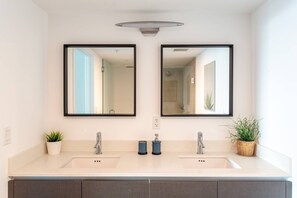 A modern bathroom with two sinks, a mirror above each sink, and a ceiling light fixture. - Luxurious 2BR, Pool, Hot tub, Sauna, Gym, Parking, Min to Beach (Miami Beach)