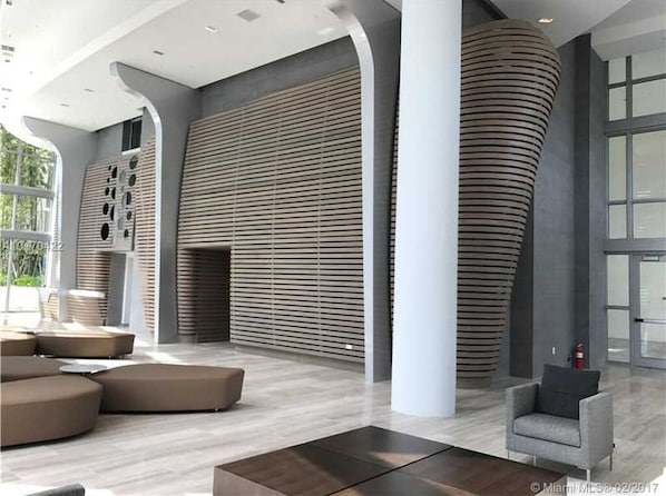 A modern interior with curved columns, a large seating area, and a large window providing natural light.