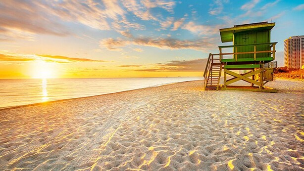 Ein Rettungsturm am Strand, im Hintergrund ein Sonnenuntergang.