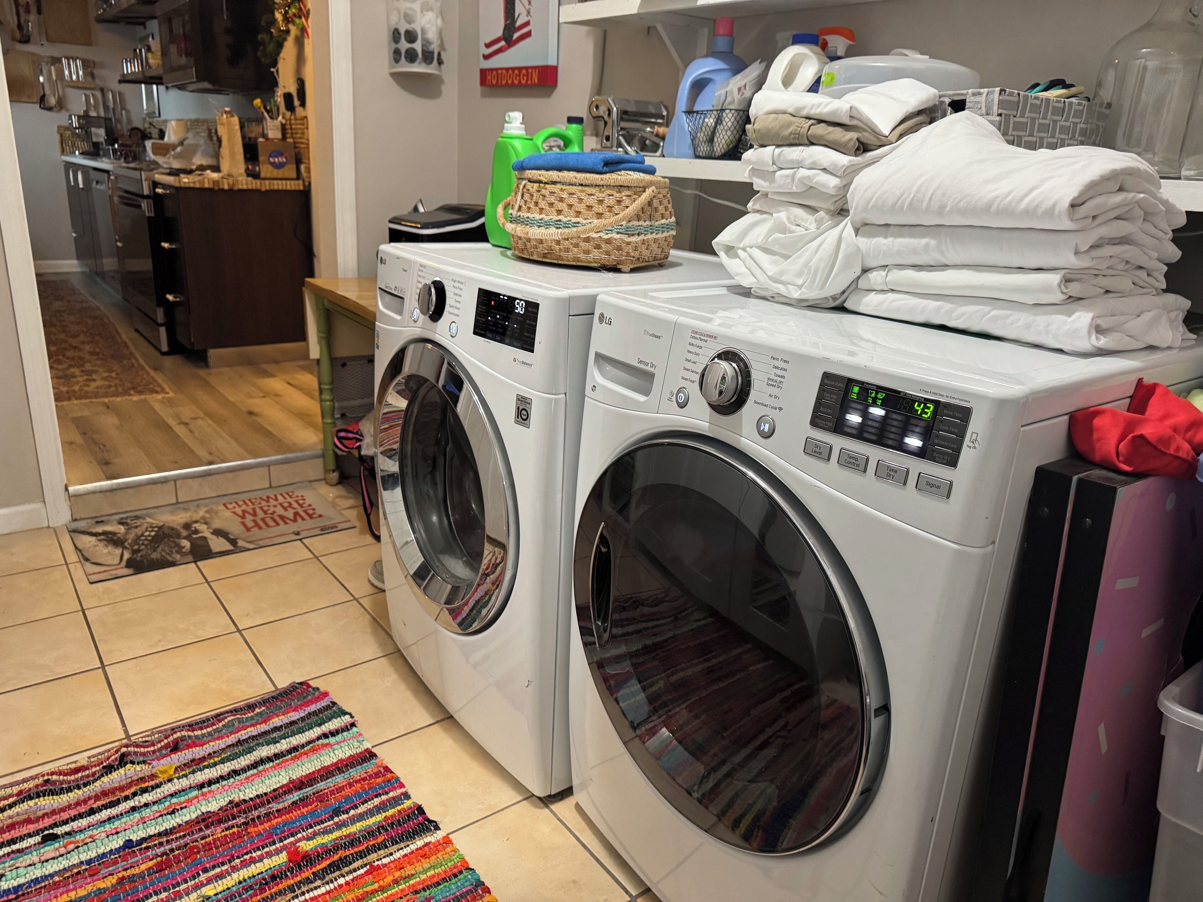 A laundry area with two front-loading washing machines, a wicker basket, and a stack of folded towels.
