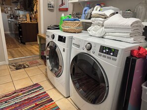 A laundry area with two front-loading washing machines, a wicker basket, and a stack of folded towels.