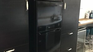 Une cuisine avec un réfrigérateur noir, un plan de travail en bois et un tapis à motifs.