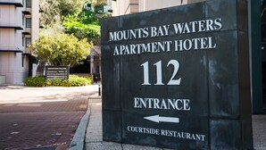 Schild für das Mounts Bay Waters Apartment Hotel, Eingang 112, mit Pfeil zum Courtside Restaurant.