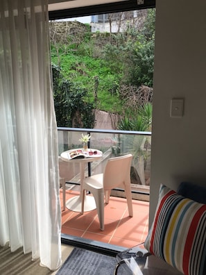 Relax on the balcony with a view of lush greenery and a stone wall.