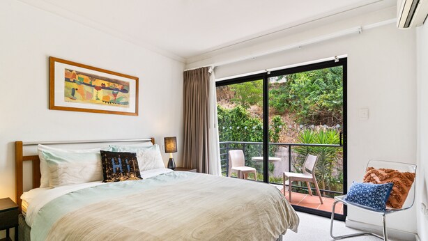 Ein Schlafzimmer mit einem großen Bett, einem Bild an der Wand und einem Balkon mit Gartenmöbeln.