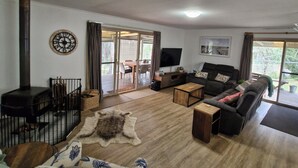 Uma sala de estar com lareira, sofá, mesa de centro e televisão.