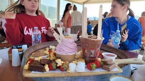 Uma mesa de jantar com diversos doces e bebidas, incluindo sorvete, morangos e uma garrafa de água.