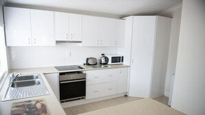 A compact kitchen with white cabinets, a microwave, a kettle, and a toaster. - Family Friendly, light & bright ideal for short or longer stays (York)