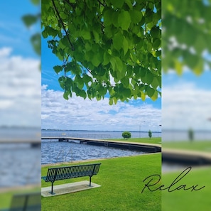 A bench by a calm water body with a bridge in the background.