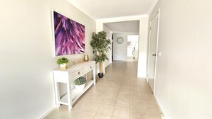 A hallway with a white console table, a large purple abstract painting, and a potted plant. - Hyland Hideaway Yarrawonga (Yarrawonga)