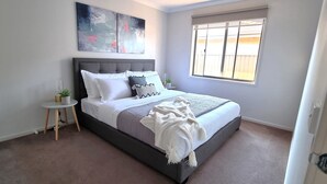 A bedroom with a bed, a small side table, a window, and abstract art on the wall. - Hyland Hideaway Yarrawonga (Yarrawonga)